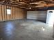 Spacious garage featuring a large door, a side entry door, and an unfinished interior at 600 Fairlane Dr, Edinburgh, IN 46124