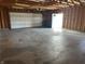 Open garage featuring a large garage door, side entry door, and concrete flooring at 600 Fairlane Dr, Edinburgh, IN 46124