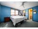 This bedroom features a light-filled window, neutral carpet, blue walls and attached bathroom at 617 Kokomo Ln, Indianapolis, IN 46241
