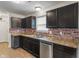 A view of the kitchen with a double sink, brick backsplash, stainless steel appliances, and dark cabinets at 6316 Avacado Dr, Indianapolis, IN 46217