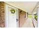 Covered front porch showcasing the brickwork, white door with wreath, and ambient outdoor lighting fixture at 6436 Lakeland Blvd, Indianapolis, IN 46234