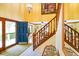 Bright foyer with a blue front door, staircase with wood railings, and a glimpse into the living room at 6761 E Woodland Ct, Mooresville, IN 46158