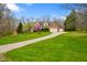 A charming brick home with a three-car garage is showcased with mature trees in the front and winding driveway at 6761 E Woodland Ct, Mooresville, IN 46158