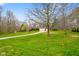 A serene shot of a brick home with a long driveway, nestled amongst mature trees and a lush green lawn at 6761 E Woodland Ct, Mooresville, IN 46158