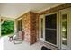 A charming brick porch featuring comfortable seating and a decorative glass front door at 6761 E Woodland Ct, Mooresville, IN 46158