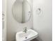 Simple bathroom with a pedestal sink, round mirror, and neutral wall color at 693 Cembra Dr, Greenwood, IN 46143
