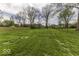 The property features a large, grassy backyard with mature trees, and a wooden fence in the distance at 7144 Lockwood Ln, Indianapolis, IN 46217