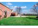 Large backyard with green grass, red brick house, grill, and partially covered pool at 7265 Derbyshire Dr, Cumberland, IN 46229