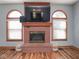 Elegant brick fireplace with arched windows on either side and dark wood floors at 7265 Derbyshire Dr, Cumberland, IN 46229