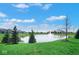 Scenic view of a pond with a fountain surrounded by green grass and neighborhood houses at 7265 Derbyshire Dr, Cumberland, IN 46229