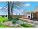 Landscaped front yard with flowers, trees, brick home, covered porch, and gravel at 7265 Derbyshire Dr, Cumberland, IN 46229