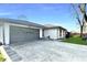 Charming one-story home featuring a gray two-car garage, landscaped yard, and white painted brick at 7606 Miracle Rd, Indianapolis, IN 46237