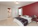 Cozy bedroom features a plush bed with plaid throw, red accent wall, and a connected bathroom at 8160 Shaldon Ct, Zionsville, IN 46077