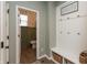 Mudroom with bench, hooks, storage baskets, and view into powder room with accent wall at 8160 Shaldon Ct, Zionsville, IN 46077