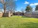 Large grassy backyard featuring a wooden fence, fire pit and cabana at 919 Oak Park Dr, Shelbyville, IN 46176