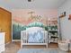 Decorated bedroom featuring a playful mural, white crib, and ample shelving filled with toys and books at 919 Oak Park Dr, Shelbyville, IN 46176