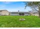 View of the backyard with a fire pit and a well maintained, lush green lawn at 9328 Haddington W Dr, Indianapolis, IN 46256