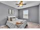 Cozy bedroom with gray walls, neutral carpet, ceiling fan, and coordinated decor at 9328 Haddington W Dr, Indianapolis, IN 46256