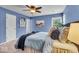 Comfortable bedroom with blue walls, neutral carpet, ceiling fan, and a coordinated bedding set at 9328 Haddington W Dr, Indianapolis, IN 46256