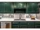 This kitchen features dark green cabinets, stainless steel appliances, white countertops, and a white and green backsplash at 9435 Tamarack Dr # 94, Indianapolis, IN 46260