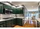 This kitchen features dark green cabinets, stainless steel appliances, white countertops, and a white and green backsplash at 9435 Tamarack Dr # 94, Indianapolis, IN 46260