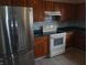 A kitchen with stainless steel refrigerator, stove, wooden cabinets, and tile backsplash at 10629 Simsbury Ct, Indianapolis, IN 46236