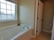 A luxurious soaking tub is placed next to a window in this bright bathroom at 12866 Thames Dr, Fishers, IN 46037