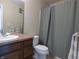 Bathroom featuring a single-sink vanity, toilet, mirror, and shower with green curtain at 12866 Thames Dr, Fishers, IN 46037