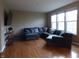 Comfortable living room with hardwood floors, large sectional sofa, and bright windows at 12866 Thames Dr, Fishers, IN 46037