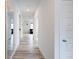 Hallway featuring light wood floors, white trim, and a large mirror at 15702 Cobbs Crk Ln, Noblesville, IN 46060