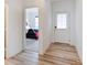 Hallway featuring light wood floors, a white door, and a view of a bedroom at 15702 Cobbs Crk Ln, Noblesville, IN 46060