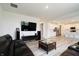 Open-concept living room featuring modern floors, a black leather sofa, and an open kitchen at 15702 Cobbs Crk Ln, Noblesville, IN 46060