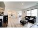 Open-concept living room with modern floors, black leather sofas, and an open kitchen area at 15702 Cobbs Crk Ln, Noblesville, IN 46060