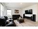 Living room featuring modern floors, a black leather sofa, and natural light from a window at 15702 Cobbs Crk Ln, Noblesville, IN 46060