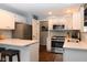 Well-lit kitchen boasts modern stainless steel appliances, white cabinets, and a breakfast bar at 16 Corkwood Ct, Brownsburg, IN 46112