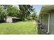 Large, grassy backyard with a storage shed, patio area, and mature shade trees at 2126 Dawnshire Dr, Columbus, IN 47203