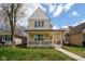 Charming two-story home featuring a covered front porch, neutral siding, and lush green lawn at 2209 Carrollton Ave, Indianapolis, IN 46205
