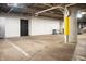 Basement storage area with visible pipes, concrete supports, and a black door at 225 N New Jersey St # Apt 48, Indianapolis, IN 46204