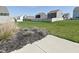 Spacious backyard with a mix of green grass and yellow dandelions, surrounded by a wooden fence and neighboring homes at 321 Bluestem Ln, Whiteland, IN 46184