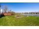 Green backyard with garden beds and a wooden deck overlooking a serene lake, perfect for outdoor enjoyment at 3634 W 58Th St, Indianapolis, IN 46228