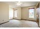 Spacious bedroom featuring neutral carpet, a ceiling fan, two windows for natural light, and a wood door at 3634 W 58Th St, Indianapolis, IN 46228