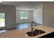 Bright, open kitchen with white countertops, stainless steel sink, and a view to the living room at 3933 Donaldson Creek Ct, Clayton, IN 46118