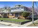 Two-story gray home with a brick porch, manicured lawn, and vibrant flowering trees enhancing its appeal at 3970 Broadway St, Indianapolis, IN 46205