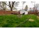 Spacious backyard with green grass, fire pit, storage and picnic table under trees at 4547 Farrington Ave, Indianapolis, IN 46201