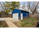 A blue detached garage with a white garage door, side door and a small yard is perfect for extra storage and parking at 5252 N College Ave, Indianapolis, IN 46220