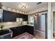 Modern kitchen with black cabinets, stainless steel refrigerator, and stone countertops at 5333 Thicket Hill Ln, Indianapolis, IN 46226