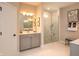 Bright bathroom featuring gray cabinets, double sinks, and a glass-enclosed shower with marble surround at 7282 Portico Ln, McCordsville, IN 46055
