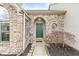 Charming brick home entrance with arched doorway, green door, and manicured landscaping at 7715 High View Cir, Indianapolis, IN 46236