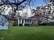 View of the backyard featuring a sunroom, storage shed, and beautiful flowering trees at 7740 5 Points Rd, Indianapolis, IN 46259