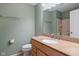 Bathroom features light green walls, neutral accents and a wood vanity with integral sink and toilet at 8235 Picadilly Ln, Indianapolis, IN 46256
